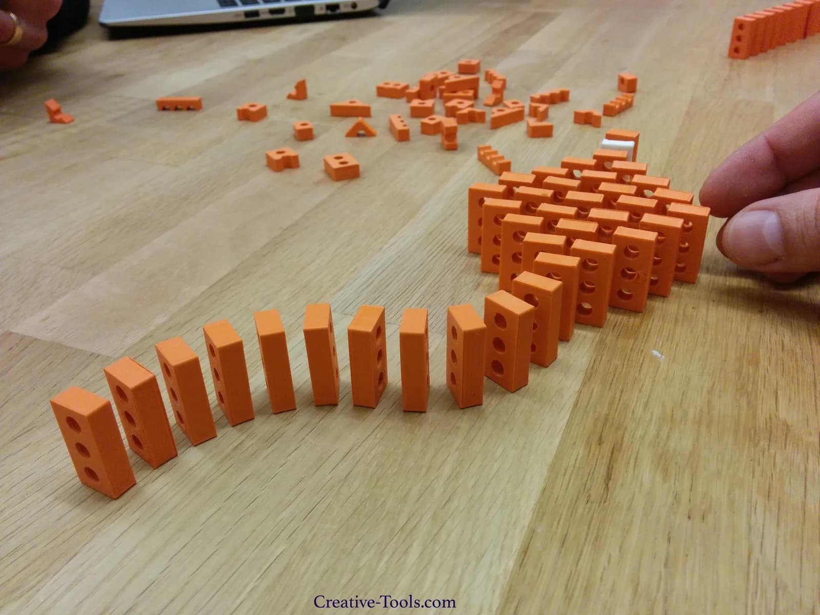 Repeated orange 3D-printed blocks arranged in rows on a wooden table